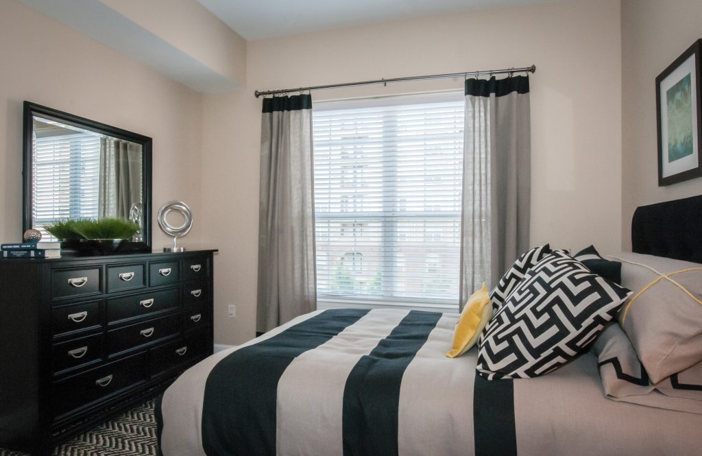 A black and white bedroom with a dresser and mirror in Southgate Apartments in Baton Rouge.
