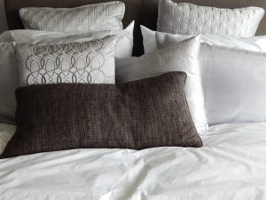A bed with white sheets and pillows.